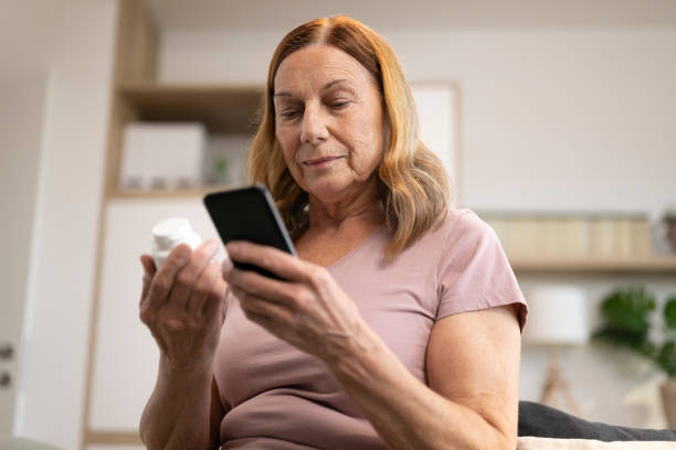 istock Woman holding pill bottle and mobile 1473708330