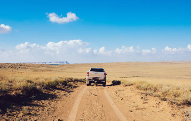 istock Car driving on sandy off road with dry grass 1473708477