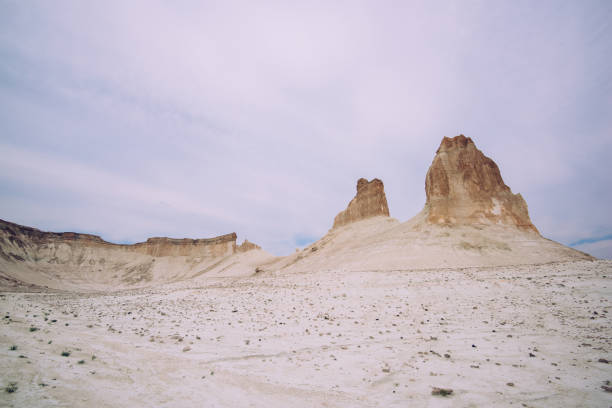 Scenic view of rocky formations in middle of dry desert valley with sandy surface covered with plants and small stones
