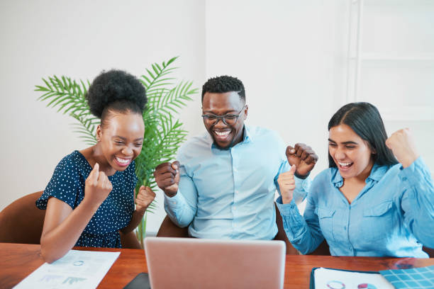 three smiling and happy coworkers cheer and celebrate success, looking at screen - cheering business three people teamwork imagens e fotografias de stock