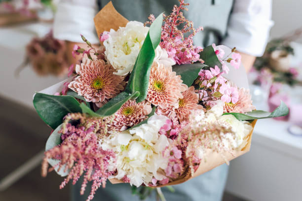 un dipendente di una boutique di fiori tiene un bouquet appena raccolto. - flower market immagine foto e immagini stock