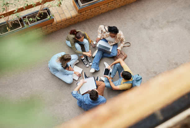 istock Study, university group and students on floor for research, project or planning, brainstorming and teamwork. Technology, education and top of college friends or people circle in school collaboration 1473712269