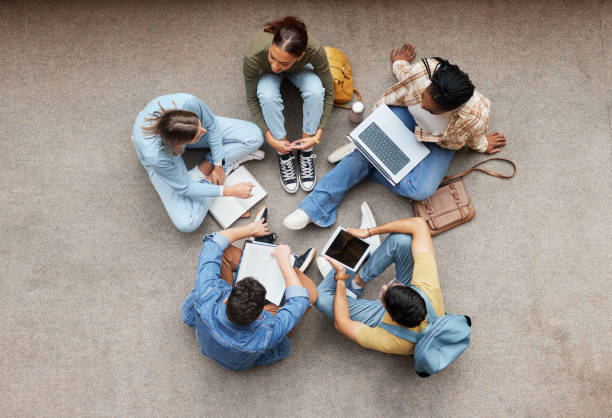 istock Study, laptop and group of students on floor in project, research or planning, brainstorming and teamwork. Notebook, education and top of university student, friends or people collaboration in school 1473712270