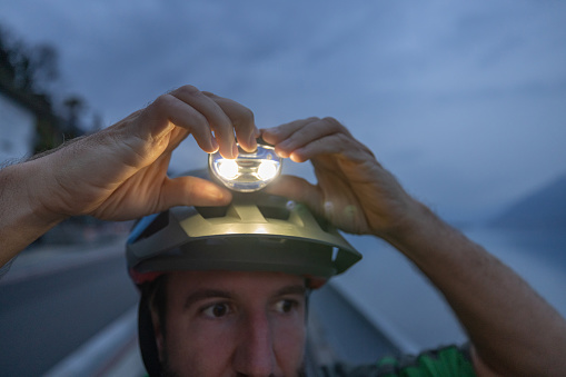 Outdoor fitness at night. Cyclist adjust headlamp on his helmet, Outdoor fitness at night
