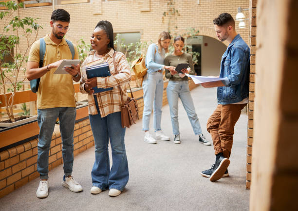 istock Students, college and education, tablet and books for learning, scholarship and collaboration in campus hallway. University with people studying together, learn with diversity and academic goals 1473716697