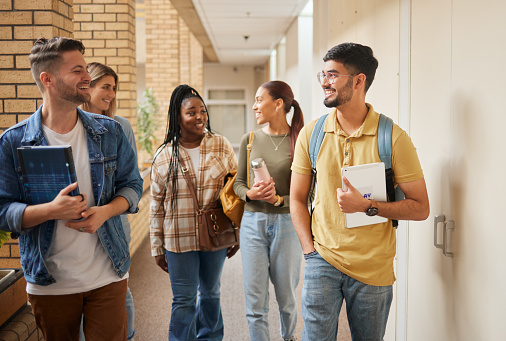 Education, diversity and students walking, conversation and collaboration for group project, research and college. Young people, friends and academics in hallway, talking and brainstorming for idea