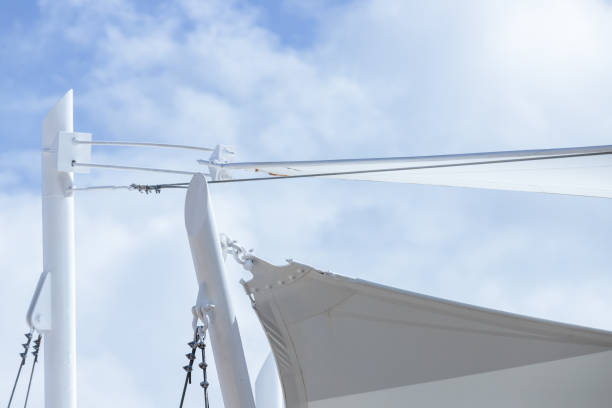 돛 모양의 흰색 차양은 밝은 푸른 하늘 아래에 있습니다. - shade sail awning textile 뉴스 사진 이미지