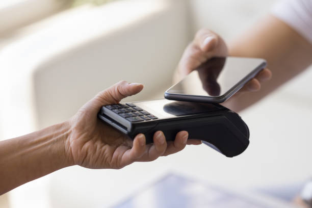 Female hand holding POS terminal, offering gadget for customer stock photo