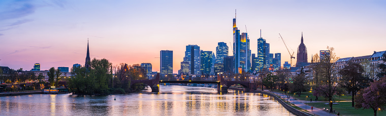 The glittering skyscrapers of Frankfurt’s Bankenviertel finance district illuminated at sunset above the bridges of the River Main in the heart of Germany’s vibrant second city.
