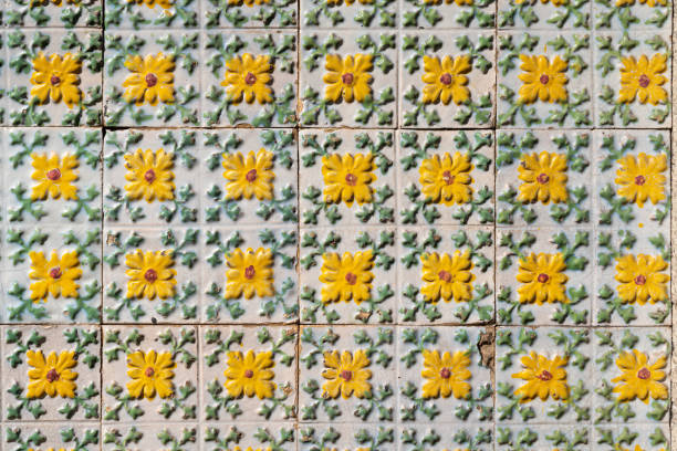 Fragment of building wall with yellow floral ceramic wall tiles Azulejo Abstract decorative background textured ornate pattern. Traditional ornate Portuguese architecture