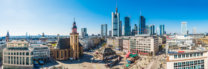 Panoramic view across the plaza of Hauptwache and stores of the Zeil shopping area overlooked by the spires of St. Catherine’s Church and the futuristic skyscrapers of Frankfurt’s central business district, Germany.