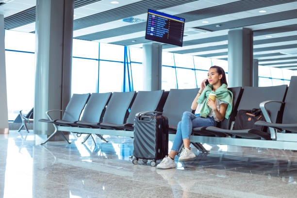 istock Young woman talking on phone while waiting for the flight 1473723692
