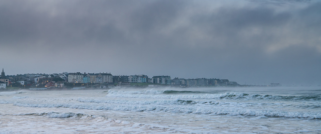 Panoramal of the town of Portrush, Northern Ireland at dusk between a stormy sky and rough seas