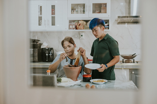 Thai lesbian couple with disability are helping to cooking their favorite dish together cooking Som Tam with mortar and pestle.