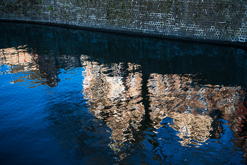 Traditional Dutch buildings reflected in abstract in the rippled blue waters of a canal in Amsterdam, Netherlands