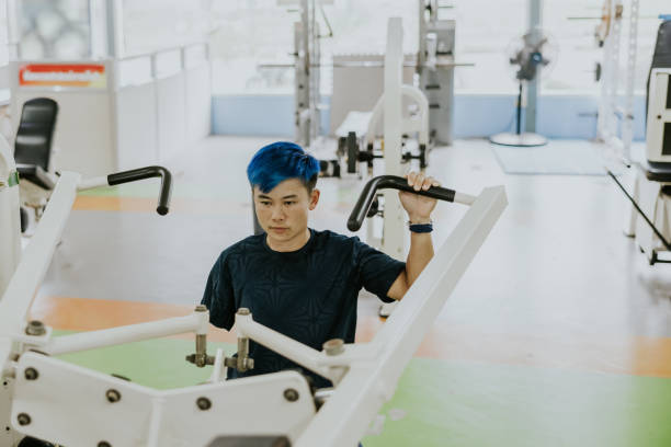 Thai para running athlete exercising with exercise machine in the gym. Thai non-binary para athlete doing exercise with exercise machine, preparing for next paralympic game. paralympic games stock pictures, royalty-free photos & images