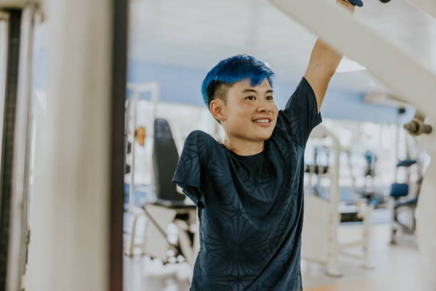 Proud and confident Para Athlete in a gym. Thai LGBTQIA people, para athlete doing exercise with exercise machine, hanging a bar with one arm. paralympic games stock pictures, royalty-free photos & images