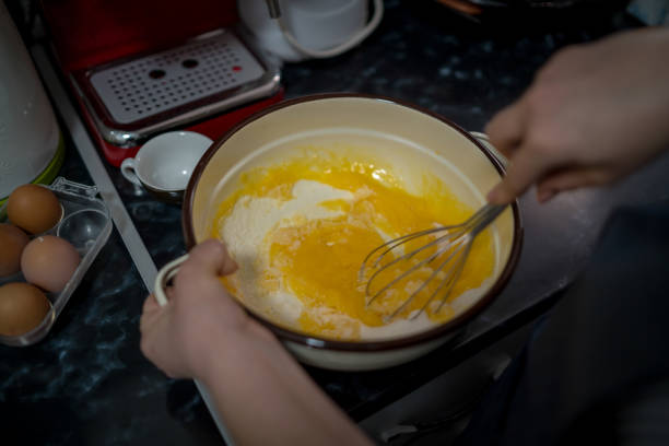 istock Young woman in a gray aprons breaks the eggs 1473730258