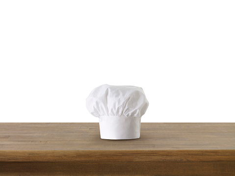 chef's hat and wooden counter in front of white background
