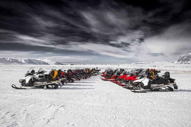 Snowmobiles parked with a mountain range in the background.