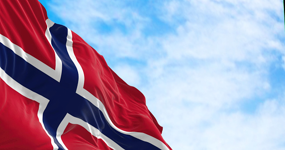Norway national flag waving in the wind on a clear day. Red field with a blue cross with white outline. 3D illustration render. Rippled textile