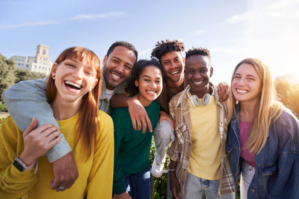 istock Young smiling happy looking at camera hugging. Group of multicultural friends having fun outdoors 1473740720
