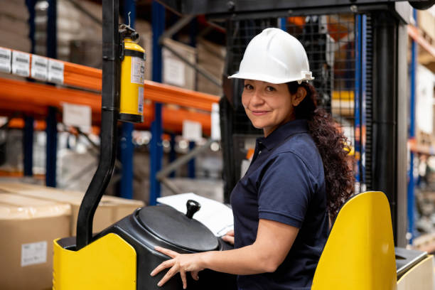 istock Happy woman driving a forklift while working at a distribution warehouse 1473740881