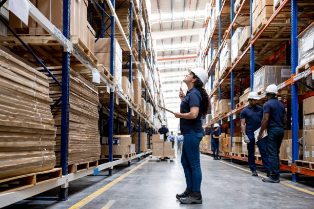 warehouse worker doing an inventory and counting the boxes of merchandise - full length clipboard african ethnicity black imagens e fotografias de stock