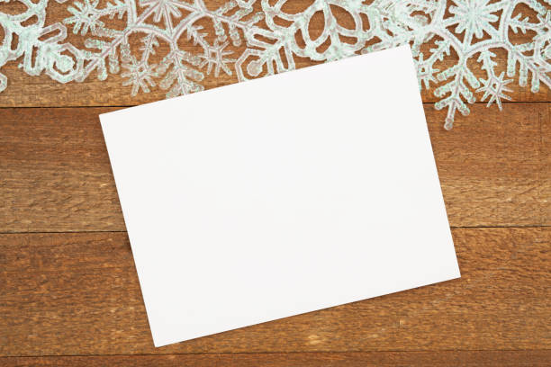 Blank white greeting card with snowflakes on weathered wood for your winter or seasonal message