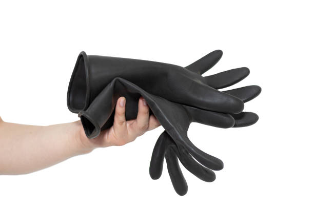 una persona che tiene due guanti di gomma neri davanti a uno sfondo bianco. - rubber sports glove equipment isolated foto e immagini stock