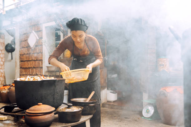 istock vietnamese woman cooking steamed fish on open fire in restaurant 1473745588