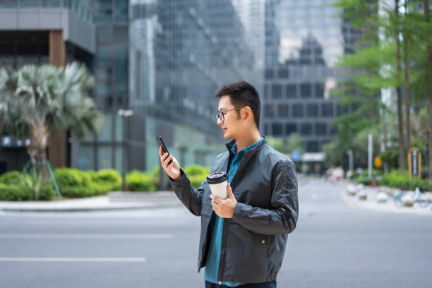 istock Chinese office worker using mobile phone with coffee at outdoors 1473746954