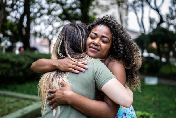 istock Female friends embracing in a park 1473748861