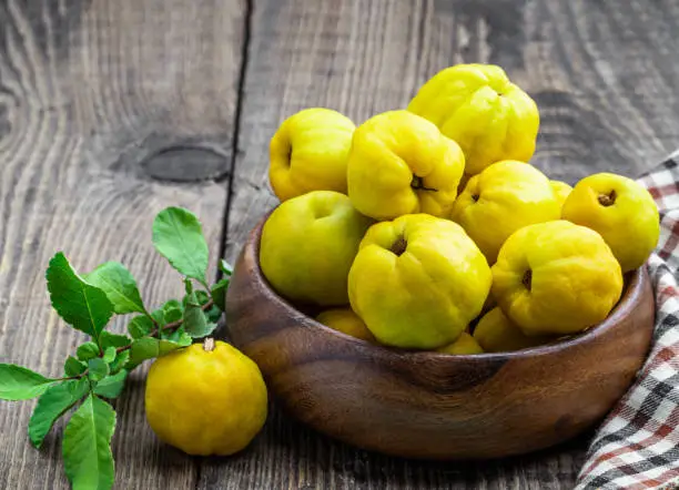 Fresh  quince fruits in wooden bowl on rustic background