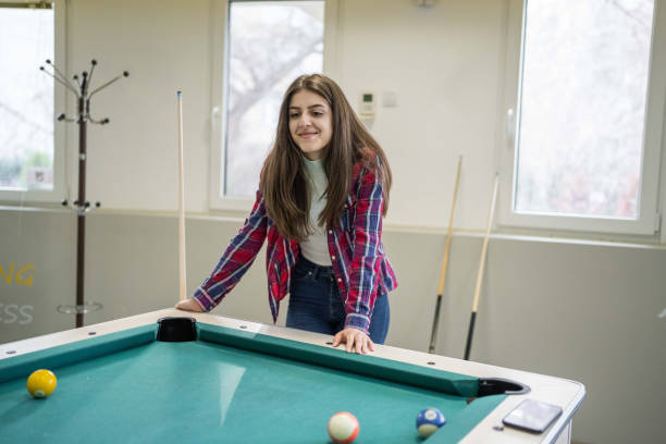Woman having fun playing snooker in modern office building playroom.