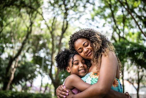 Mother and daughter embracing in a park