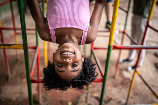 Portrait of a girl upside down in a jungle gym in a park