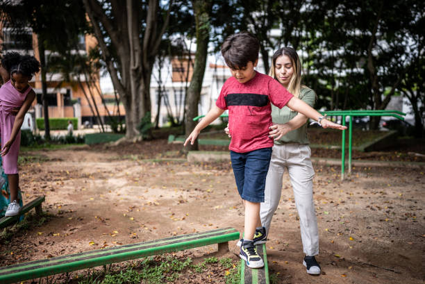 Mother helping son walking with balance in a park