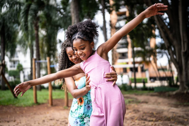 Mother helping daughter walking with balance in a park