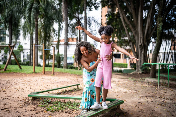 Mother helping daughter walking with balance in a park