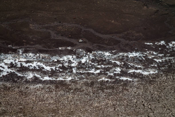 The surface, edge of glacial firn, permanent snow patch in the caldera of the volcano, near frozen crater lake during the summer melting. Salt leaching, ammonium chloride apparently