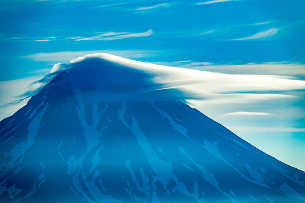 The 3500 m high active volcano is shrouded in ring lenticular cloud - rare natural phenomenon. Volcanic uplift. Kamchatka