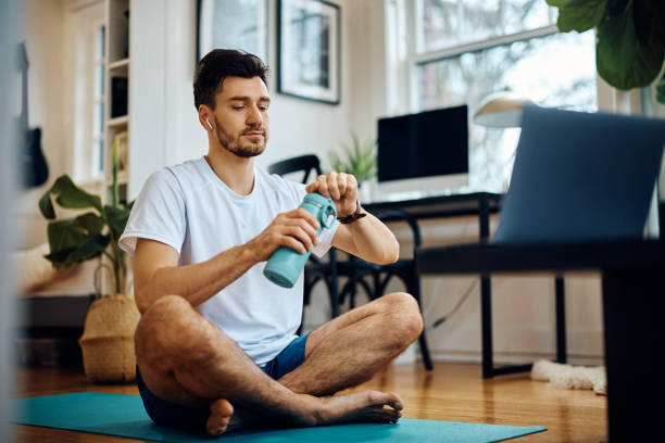 istock Athletic man having water break while working out at home. 1473762854