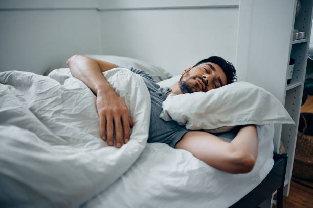 istock Mid adult man resting while sleeping in a bed. 1473762949