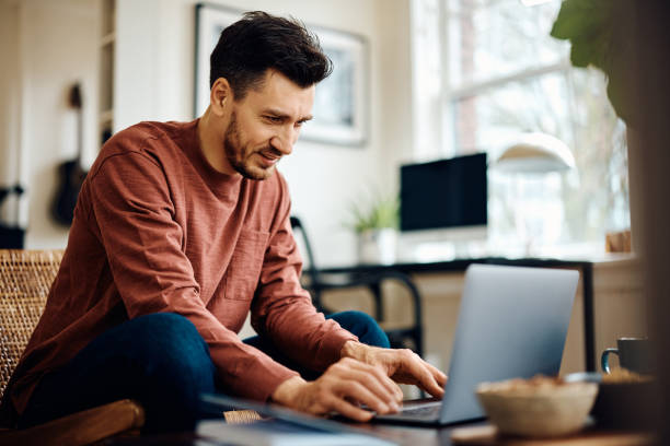 istock Happy man surfing the net on laptop at home. 1473763033