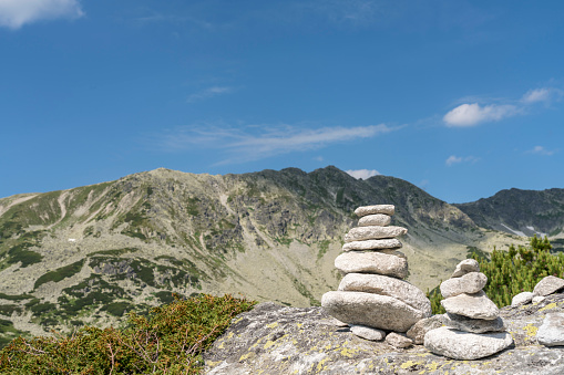Small stacks of stones marking the footpath along the mountain ridge against blue sky. Retezat mountain on sunny day.