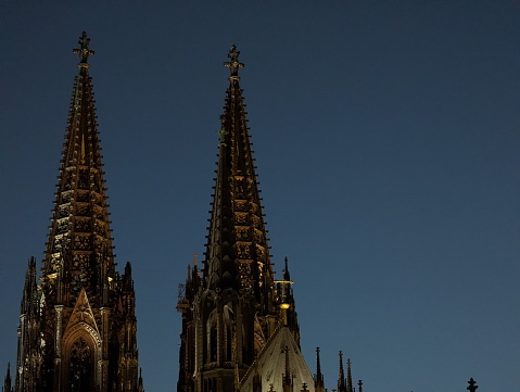 Close up of illuminated Cologne Cathedral towers and spires during a clear summer day at sunset