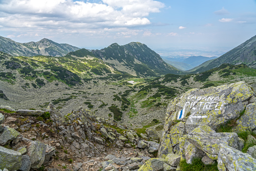 Granite rocks and trail mark showing the way. All around mountain ridge of Retezat mountains.