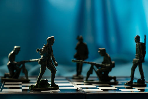 Plastic soldiers stand on a chessboard in the dark on a blue background