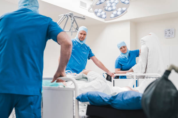 istock Team of surgeons with patient on operating bed after surgery 1473775007